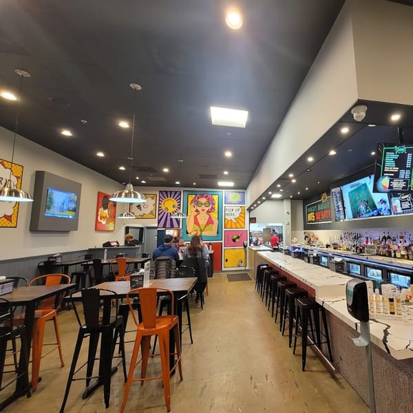 The interior of Hangry Burger features pop art, high-top tables, and a long bar with stools.