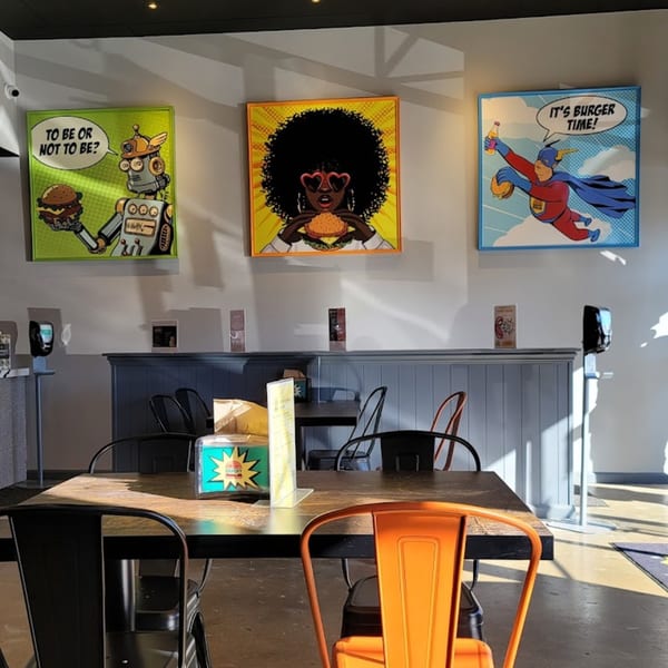 Hangry Burger dining area with comic-style burger art on the wall and tables with metal chairs.